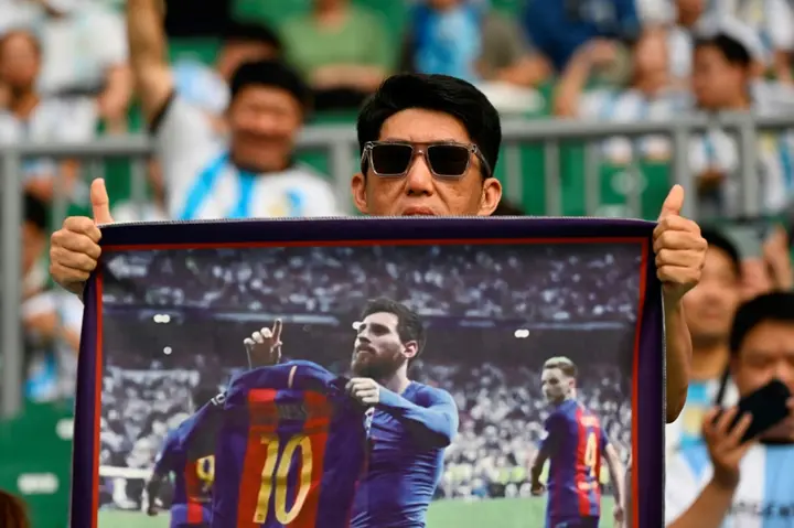 A fan holds an image of Lionel Messi at the match in Beijing
