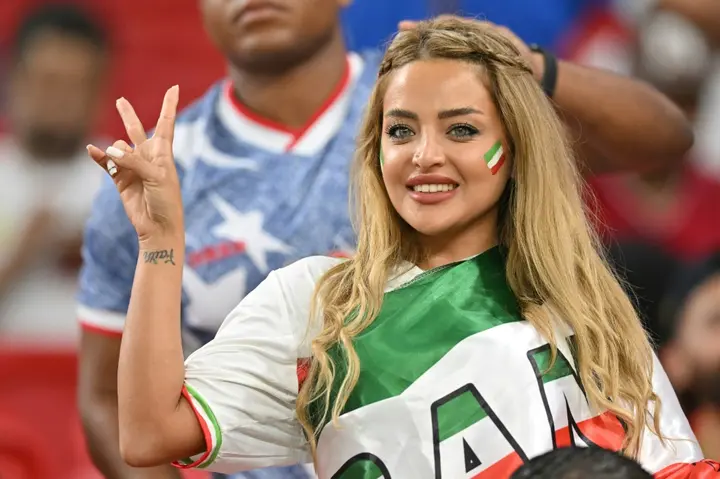 An Iran supporter, draped and painted in the national colours, cheers on her team against the US on Tuesday night