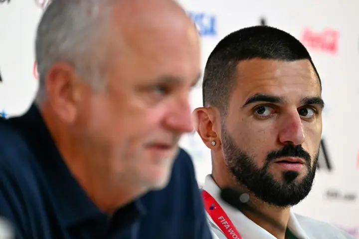 Australia's defender Aziz Behich (R) looks at coach Graham Arnold during a press conference
