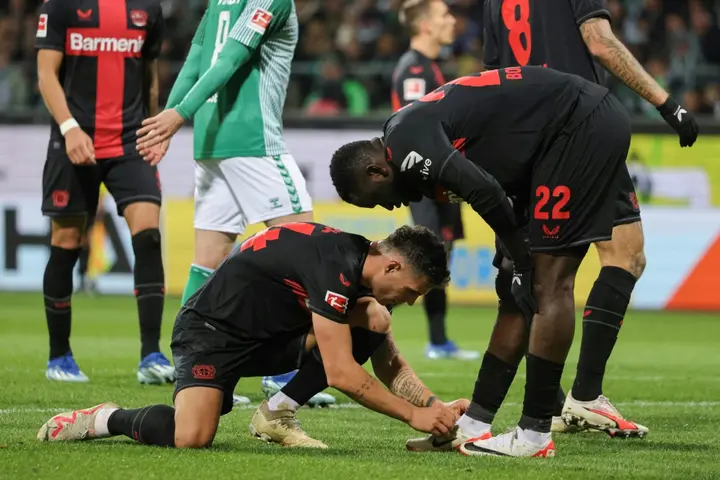 Bayer Leverkusen midfielder Granit Xhaka ties the shoe of forward Victor Boniface. Both arrived in the summer transfer window