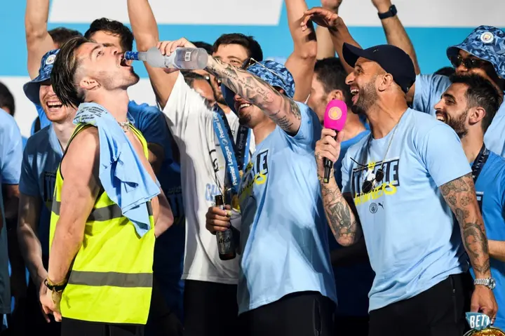 Jack Grealish (L) has vodka poured down his throat following Manchester City's open-top bus parade celebrating Champions League, FA Cup and Premier League trophies